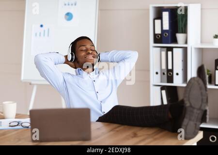 Entspannter Schwarzmann Mitarbeiter hört Musik in seinem Büro Stockfoto