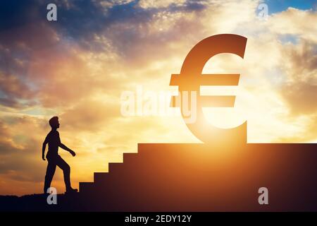 Mann, der vor einer Treppe steht und ein Euro-Schild oben hat. Geldverfolgung. Finanzen und Wirtschaft. Ziele. Stockfoto