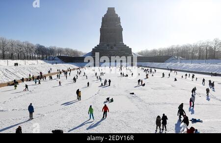 Leipzig, Deutschland. Februar 2021, 14th. Leipzigers spielen Eishockey auf dem See der tausend Tränen vor dem Denkmal zur Völkerschlacht. Nach frostfreien Tagen laden zumindest die flachen Teiche zum Eislaufen ein. Quelle: Jan Woitas/dpa-Zentralbild/ZB/dpa/Alamy Live News Stockfoto