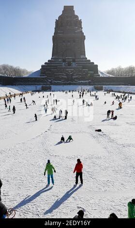 Leipzig, Deutschland. Februar 2021, 14th. Leipzigers spielen Eishockey auf dem See der tausend Tränen vor dem Denkmal zur Völkerschlacht. Nach frostfreien Tagen laden zumindest die flachen Teiche zum Eislaufen ein. Quelle: Jan Woitas/dpa-Zentralbild/ZB/dpa/Alamy Live News Stockfoto