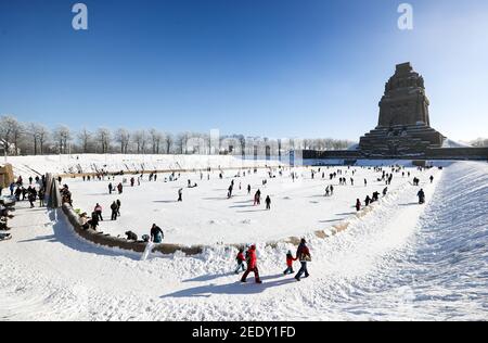 Leipzig, Deutschland. Februar 2021, 14th. Leipzigers spielen Eishockey auf dem See der tausend Tränen vor dem Denkmal zur Völkerschlacht. Nach frostfreien Tagen laden zumindest die flachen Teiche zum Eislaufen ein. Quelle: Jan Woitas/dpa-Zentralbild/ZB/dpa/Alamy Live News Stockfoto