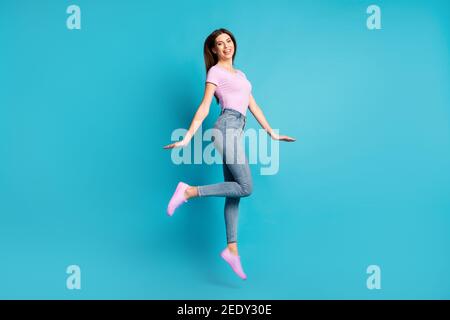 In voller Länge Profil Foto von schönen jungen Mädchen springen tragen Rosa T-Shirt Schuhe Jeans isoliert blaue Farbe Hintergrund Stockfoto