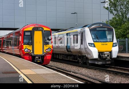 Britische Bahnlinie 387 Personenzug in Gatwick Express Lackierung und eine Klasse 700 in Thameslink Lackierung warten auf einem Bahnhofsbahnsteig, England. Stockfoto