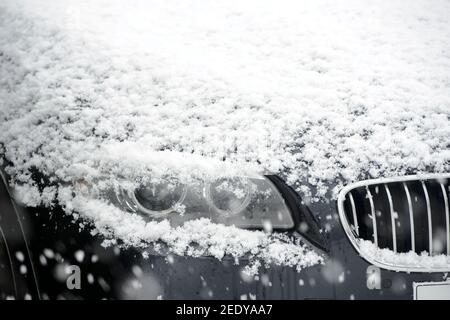 Schnee liegt auf der Motorhaube eines BMW Autos. Stockfoto