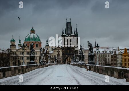 Winteransicht der Karlsbrücke, Altstädter Brückenturm mit Schnee bedeckt, Prag, Tschechische Republik. Menschen, die im kalten Winter durch die Stadt wandern Stockfoto