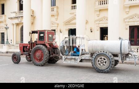 Veralteter russischer Traktor der Oldtimer fährt vor der Provinzbibliothek Jose Marti vorbei und wird in einer kubanischen Stadt zum Malen der Straßen verwendet Stockfoto