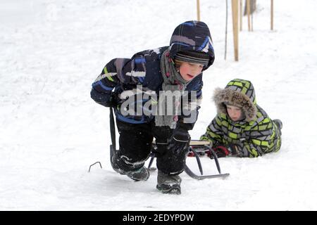 Nicht exklusiv: DNIPRO, UKRAINE - 13. FEBRUAR 2021 - Kinder klettern einen Hügel im Zelenyi Hai Park, Dnipro, Zentralukraine. Stockfoto