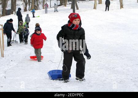Nicht exklusiv: DNIPRO, UKRAINE - 13. FEBRUAR 2021 - Kinder klettern einen Hügel im Zelenyi Hai Park, Dnipro, Zentralukraine. Stockfoto