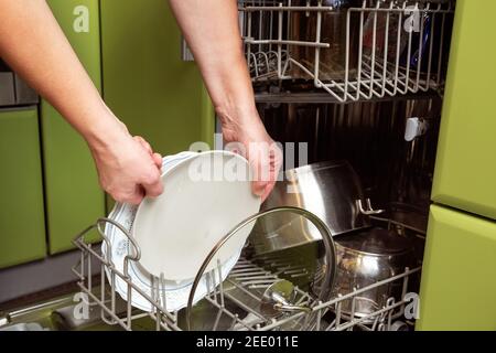 Weibliche Hände laden schmutziges Geschirr in den Geschirrspüler Stockfoto
