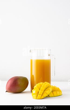 Mango-Saft in einem Glaskrug auf weißem Hintergrund, gehackte Mango und ganze, leckere gesunde süße natürliche Getränk Stockfoto