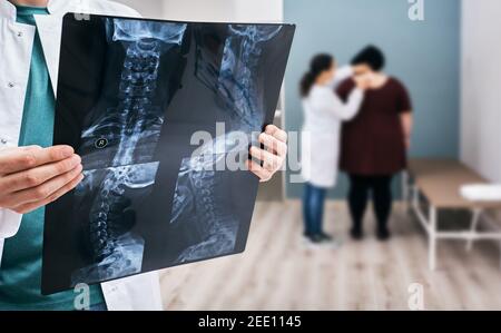 Der Arzt hält ein Röntgenbild der Halswirbelsäule über der Osteopathen-Hintergrundeuntersuchung der übergewichtigen weiblichen Wirbelsäule. Skoliose der Wirbelsäule, Diagnostik Stockfoto