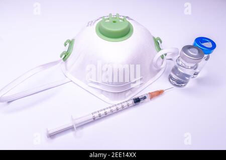 Medizinische Flasche, Vials, Spritzen und Gesichtsmaske auf blauem Hintergrund mit Kopierraum. Impfungen und Verbesserung der Immunität. Stockfoto