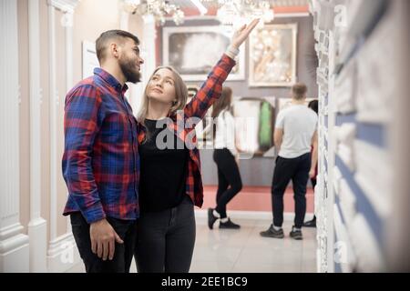 Laminat auf dem Markt, Paar Mann und Frau Arbeitnehmer wählt Parkettboden im Haus, Berater spricht über die Vorteile des Materials. Stockfoto