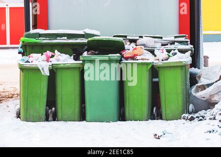 Überfließende Abfalleimer mit Hausmüll auf einem verschneiten Eis Straße Stockfoto