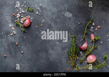 Hintergrund für das Kochen von Speisen. Gewürze Kräuter und Knoblauch an schwarzem Schiefertisch. Zutaten für das Essen von oben. Stockfoto