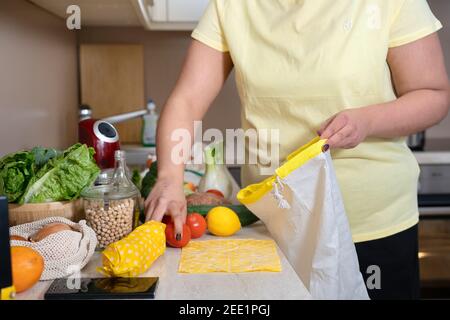 Unkenntlich Frau in gelben T-Shirt Platzierung Gemüse in Baumwolltasche Stockfoto