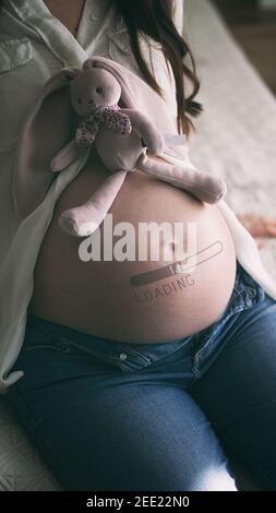 Schwangere Frau mit gemalten Ladestange auf ihrem Bauch. Warten auf Baby-Konzept Stockfoto