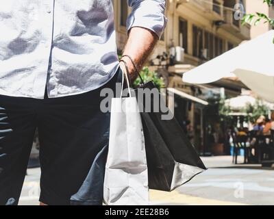 Stilvoller Mann mit zwei Taschen auf der Straße im Sommer, sonniger Tag. Konzept von Stil, Mode und Schönheit Stockfoto