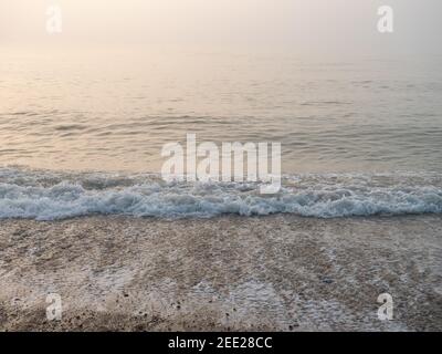 Nahaufnahme der Welle, die am Strand an der Südküste Englands an einem nebligen und nebligen Morgen im Februar bricht. Stockfoto