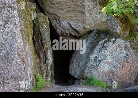 Große graue Steine umrahmen den Eingang zur Höhle im Monrepos Park in der Stadt Vyborg. Stockfoto