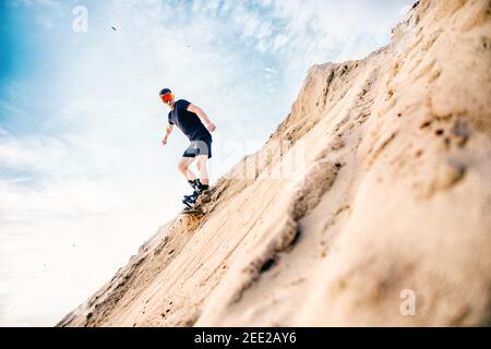 Extremer Absand auf Snowboard in der Wüste. Männlicher Snowboarder auf Dünen. Stockfoto