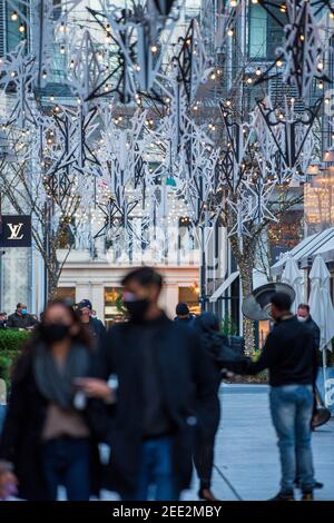 Maskierte Einkäufer schlendert durch die Palmer Alley in Washington DC. Das Stadtzentrum ist mit Lichtern und festlichen Verzierungen für die Winterurlaubsmeere geschmückt Stockfoto