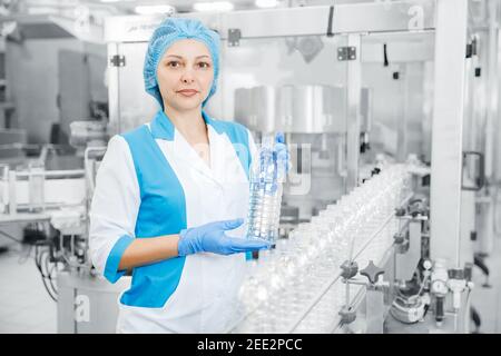 Arbeiter weiblich Überprüfung Produktionslinie Fabrik Milch Getränke in Plastikflasche. Stockfoto