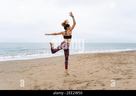 Glückliche Fitness Frau, die beim Training am Strand springt Routine Kraftübungen Stockfoto