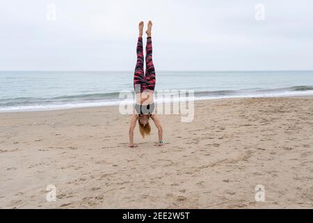 Sportliche Fitness weibliche tun Hand stehen am Strand.gesunde Frau am Meer Yoga üben, Training Balance Übung Konzept Lifestyle. Stockfoto