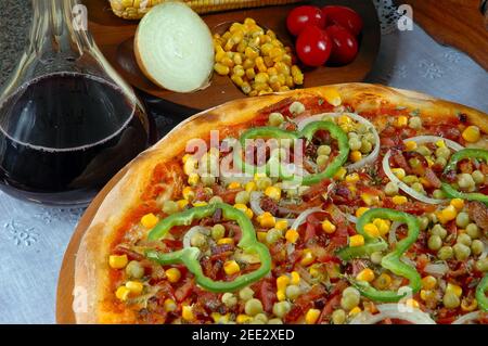 Pizza mit Mais, Speck, Paprika, Zwiebeln, Erbsen Stockfoto