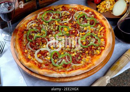 Pizza mit Mais, Speck, Paprika, Zwiebeln, Erbsen Stockfoto