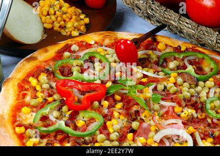 Pizza mit Mais, Speck, Paprika, Zwiebeln, Erbsen Stockfoto