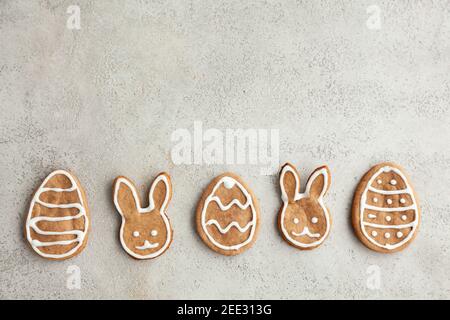 Ostern dekorierte Kekse in Form eines Hasen und Eier werden in einer Reihe auf einem grauen Hintergrund gelegt. Draufsicht Stockfoto