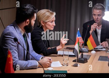 Verschiedene politische Führer sitzen und hören ältere Frau sprechen in das Mikrofon auf der Pressekonferenz im Sitzungssaal, versammelt, um IDE zu diskutieren Stockfoto