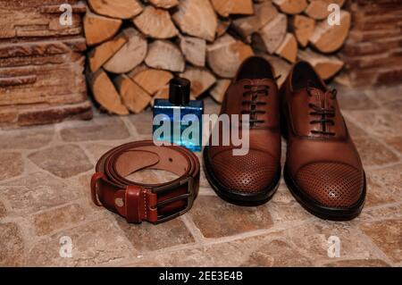 Braune Herrenschuhe. Gürtel. Parfüm. Eheringe. Accessoires des Bräutigams Stockfoto
