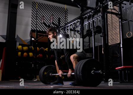 Cross-Fit-Sportler beim Hanteln im Fitnessstudio. Mann übt funktionelles Training Powerlifting Workout-Übungen allein, in Sportbekleidung. gewichtheben, Bodyb Stockfoto