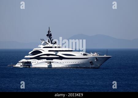 Luxusyacht mit Hubschrauberlandeplatz und Hubschraubersegeln im Meer, Seitenansicht. Weißes futuristisches Boot auf Berg Insel Hintergrund Stockfoto