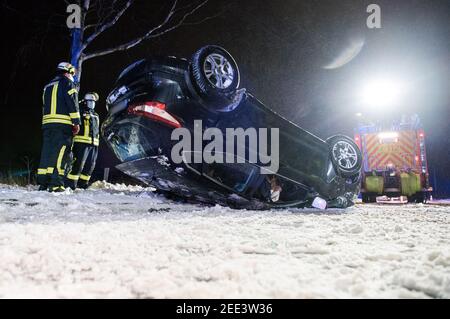 Oststeinbek, Deutschland. Februar 2021, 15th. Auf dem Dach der Landstraße zwischen Oststeinbek und Havighorst liegt nach einem Verkehrsunfall ein Auto. Der Fahrer hatte sein Auto auf der rutschigen und verschneiten Straße von der Straße gefahren, einen Baum getroffen und dann auf das Dach umgedreht. Dabei wurde der Mann verletzt. Quelle: Daniel Bockwoldt/dpa - ACHTUNG: Das Kennzeichen wurde aus rechtlichen Gründen pixeliert/dpa/Alamy Live News Stockfoto