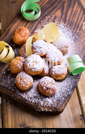 Gebackene castagnole mit Puderzucker und Konfetti. Street Food, runde Kekse mit Zucker für den Karneval von Venedig. Traditionelles süßes Gebäck während der Karnevalszeit in italien. Copy space Stockfoto