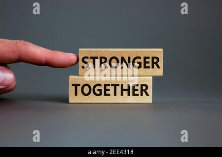 Stärker zusammen Symbol. Konzeptworte "stärker zusammen" auf Holzblöcken auf einem schönen grauen Hintergrund. Geschäftsmann Hand. Geschäft, Motivation Stockfoto