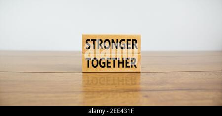 Stärker zusammen Symbol. Konzeptworte "stärker zusammen" auf Holzblöcken auf einem schönen Holztisch, weißer Hintergrund. Business, Motivation und Stockfoto