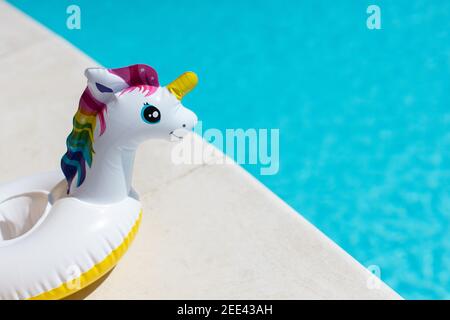 Aufblasbares pinkes Mini-Regenbogen-Einhorn, Cocktail-Stand in der Nähe von Schwimmbad an hellen sonnigen Tag, Kopierraum. Konzept Sommerurlaub, Unterhaltung, Wasser Stockfoto