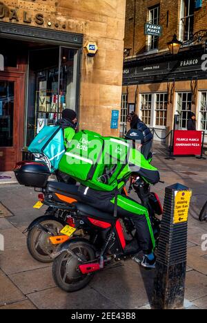 UBER Eats und Deliveroo Food Delivery Kuriere warten auf die Abholung der Bestellung außerhalb der Franco Manca Pizzeria in Cambridge UK. Stockfoto