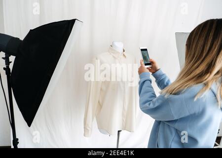 AR VR-Technologie in der Modeindustrie. Weibliche Designer Schrottung Kleidung auf Schaufensterpuppe per Handy für Augmented Reality Anwendung. AR VR-Lösungen Stockfoto