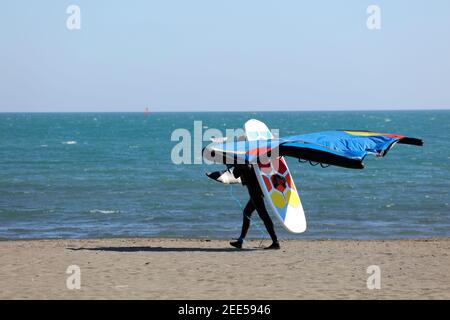 Mann, der am Strand mit Tragflügelboot und Gleitschirmfliegen läuft, (Flügelsurfer) Stockfoto