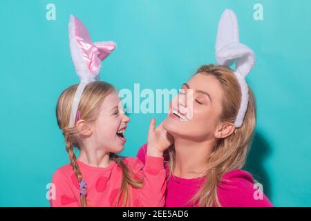 Glückliche Mutter und Kind Tochter Ostern feiern. Nettes kleines Mädchen mit lustigen Gesicht in Hasen Ohren lachen, lächeln und Spaß haben. Stockfoto