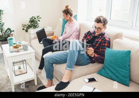 Kaukasisches Paar zu Hause sitzen im Bett und arbeiten aus Der Computer, während Sie einen Tee mit Sandwiches trinken Stockfoto