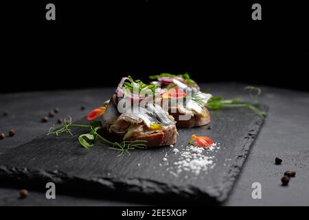 Sandwiches mit Fischtüll auf schwarzem Hintergrund. Brussquettes Stockfoto