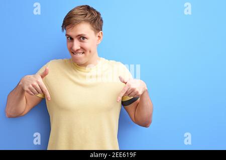 Lächelnder Mann zeigt Zeigefinger nach unten, zeigt etwas, Werbung Konzept. Menschen aufrichtigen Emotionen Lifestyle-Konzept. Mock up copy space Stockfoto
