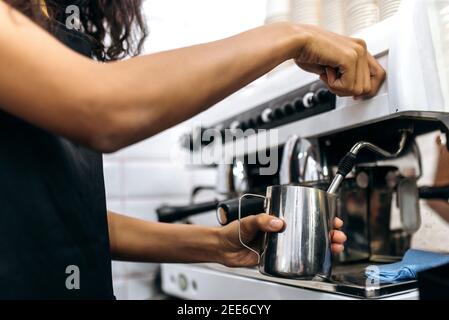 Nahaufnahme des Kaffees. Barista Mädchen bereitet Kaffee, gießt Milch für einen Cappuccino mit Kaffeemaschine Stockfoto